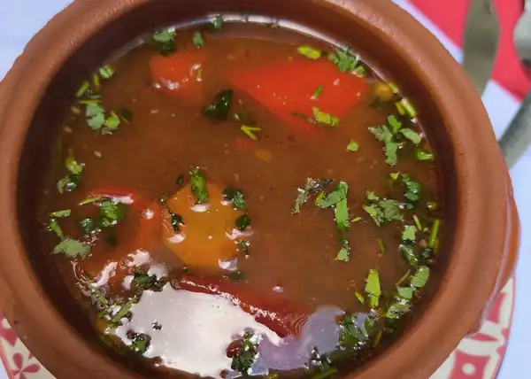 Zupa w glinianym garnku na stole z kwiecistym obrusem